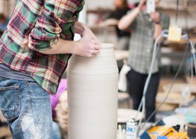 A student snaps pictures of Ben Skiba's technique throwing a tall pot in the Ceramics Lab at the Art Lofts.