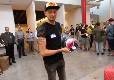 Graduate student Justin Eccles passes out customized trucker hats at the Art Department new graduate orientation event at the Art Lofts Building at the University of Wisconsin-Madison.