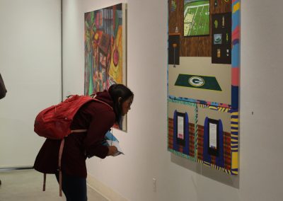A student examines the writing on a painting at the First Year Grad Show, Witnesses, on display at the Art Lofts Gallery.