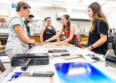 Students work in the printmaking labs in Mosse Humanities Building at the University of Wisconsin-Madison during assistant professor Emily Arthur's (in red apron) Relief Printing course.