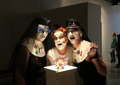 Drag performers pose with a metals piece by Matt Mauk at his Master of Arts Exhibition "Hothouse," Art Lofts Gallery, Department of Art University of Wisconsin-Madison