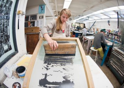 Undergraduate Sigrid Hubertz uses a squeegee to make a printed image in a water-based screen-printing class in the George Mosse Humanities building at the University of Wisconsin-Madison.