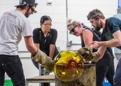 Students work together with an assortment of tools and blown air to shape a piece of molten glass and form Madison's largest glass ornament during a UW Glass Lab event in the Art Lofts Building at the University of Wisconsin-Madison. The public event featured students performing a number of interesting glass experiments and working together to create a giant Christmas ornament that was auctioned off for charity.