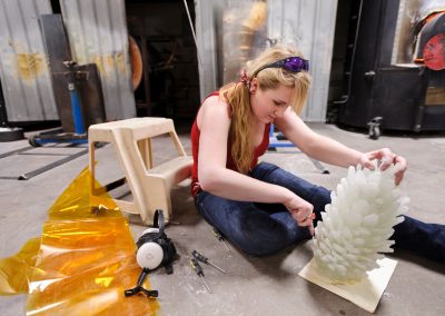 Elise Berry cleans plaster-cast remnants from a glass sculpture she is finishing in the UW Glass Lab at the University of Wisconsin-Madison.