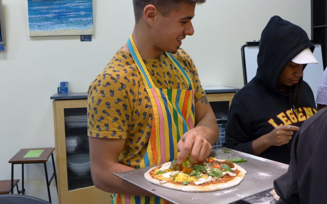 Local artist and Making Justice partner Carlos Gacharná, BFA '16, helps teens in the class make pizza.