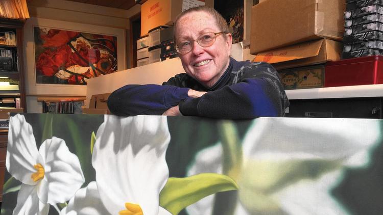 Winifred Godfrey leans on one of her signature oil paintings of flowers. Godfrey won one of the first competitive art shows at the Beverly Arts Center. She is returning as the community art center at 2407 W. 111th Street celebrates its 50th anniversary. (Howard Ludwig/Daily Southtown)