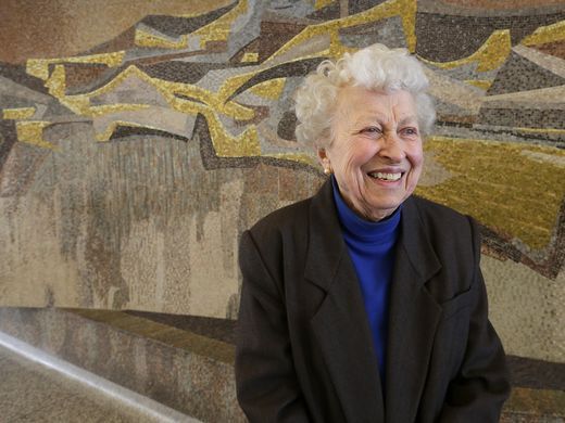 Artist Marjorie Kreilick, 93, stands in front of a mosaic she created at the Milwaukee State Office Building, 819 N 6th St. With the building up for sale, the future of the mosaics is uncertain.