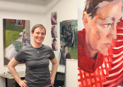 Graduate art student Noel Ash poses with her paintings in her studio space in the Art Lofts building at the University of Wisconsin-Madison.
