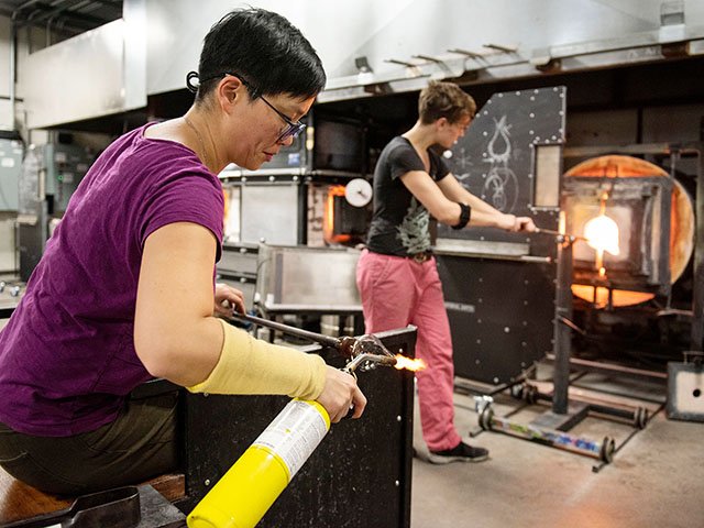 Professor Helen Lee, left, works on a glass goblet with help from graduate student Anna Lehner in the Glass Lab of the Art Lofts.