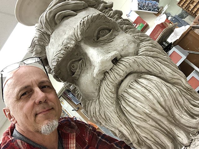 Sculptor Phil Lyons poses with one of his art pieces.