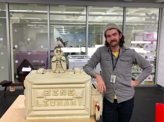 Taylor Wright Rushing at the Bubbler with his Zine Library woodworking sculpture.