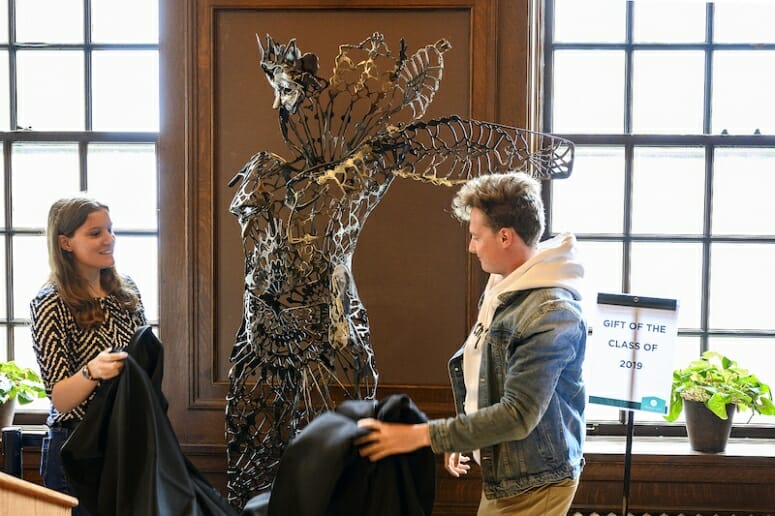 Senior class officers Mara Matovich (left) and Ronald Steinhoff (right) remove the temporary cover during a reveal event for the 2019 Senior Class Statue, titled “The Monarch,” inside the Hamel Reading Room at the Memorial Union. The statue celebrates the 150th anniversary of women receiving degrees at UW–Madison and was designed by artist Victoria Reed.