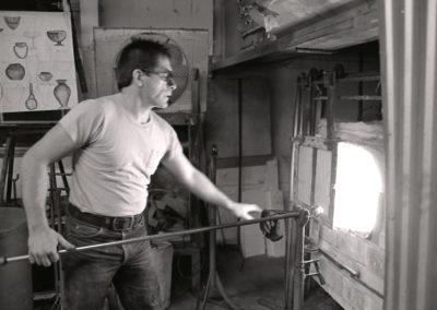 In the November of 1985, art student Rick Findora reheats molten glass on the end of a blowpipe in the glory hole furnace in the hot glass lab. Findora graduated with a BFA in 1986.