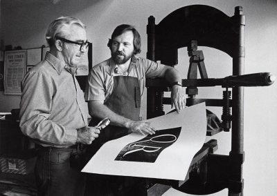Donald Anderson (left) and Phil Hamilton, both professors of art, look at a print at a press, ca. 1973.