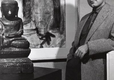 Bill H. Armstrong, an assistant professor in the department of art education from 1955 to 1963, poses with a painting and sculpture from Burma.