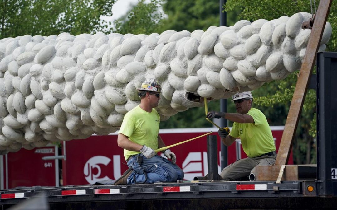 Workers secure "Nails' Tales" to a truck bed Wednesday morning. The concrete obelisk will be stored about 15 miles away on UW-Madison property until officials identify a new location for the sculpture.