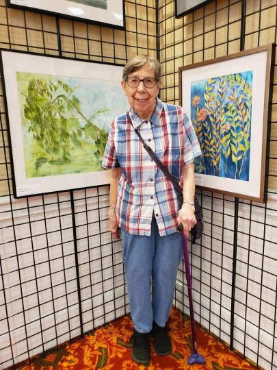 Janet Heinicke [MA '56] posing in front of her artwork.