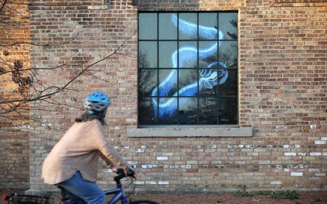 Diane Agens of Madison bikes around Garver Feed Mill. Visitors are encouraged to keep their distance from the displays. Photo by Amber Arnold.