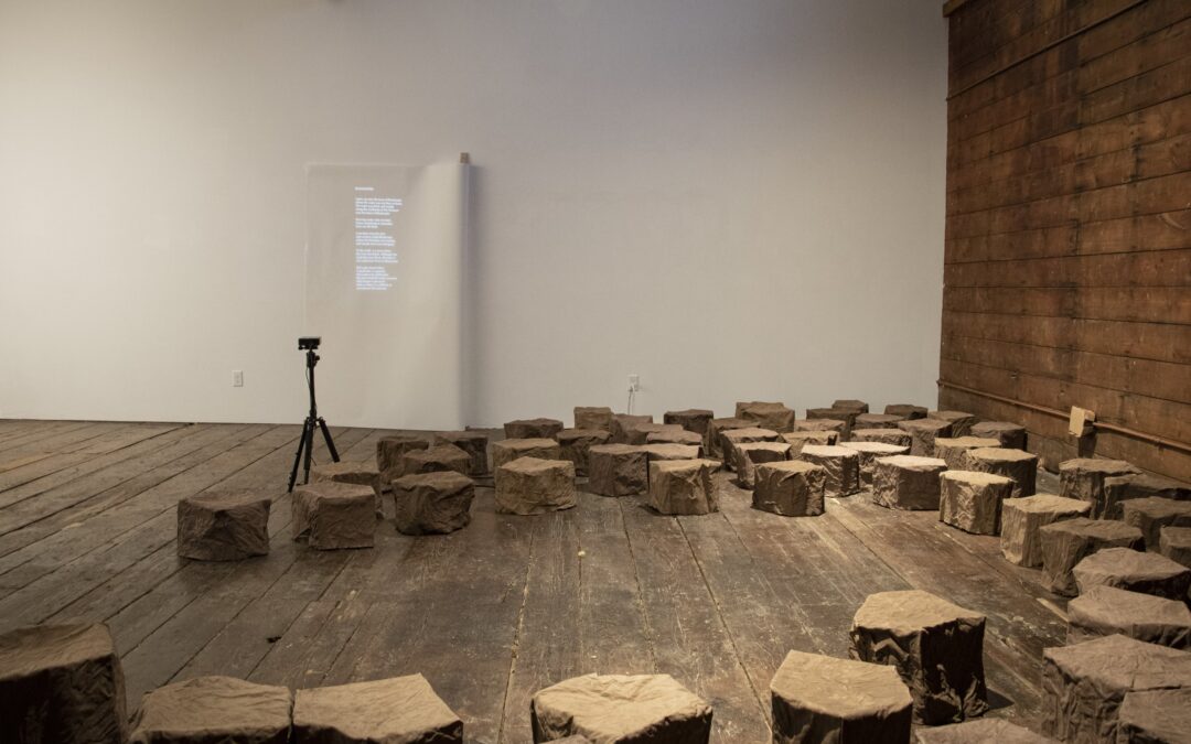 Photo: An installation of several dozen pieces, each about a foot high, emulates the color and texture of dried mud and sediment in a lakebed . The pieces are shown arrayed across the dark wooden floor of a gallery space at Abel Contemporary Gallery in Stoughton. Photos courtesy of Helen Hawley.