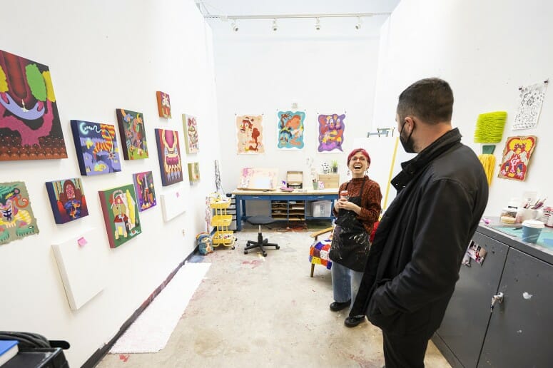 Second-year graduate painting student Jana Marie Cariddi (left) talks with a guest about her paintings in her studio space in the Arts Lofts Building. PHOTO BY: BRYCE RICHTER