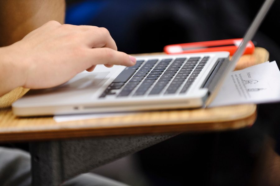 An open macbook with a hand typing on the keyboard