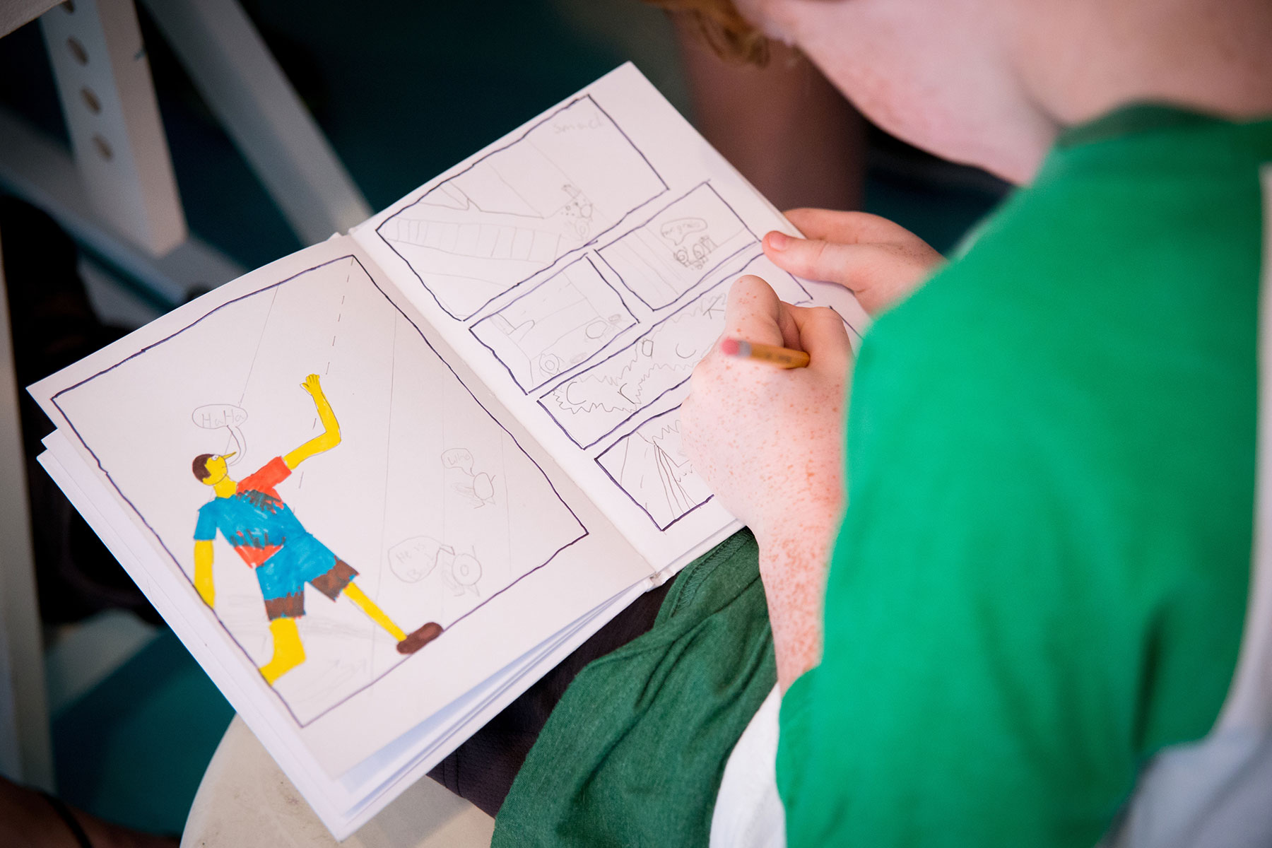 A participant at Graphic Novel Writing Camp draws the illustrations to their story in a sketch book