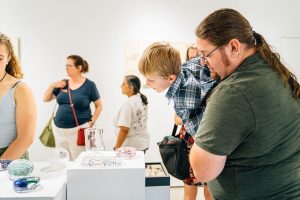 Man holds child while looking at art work in the gallery