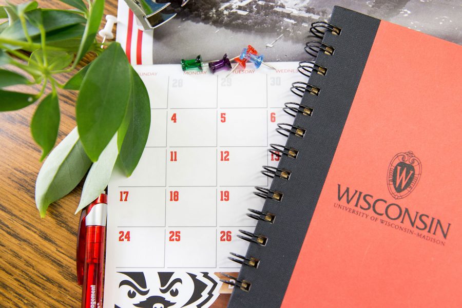 A calendar planner with a uw-madison spiral notebook on top of it