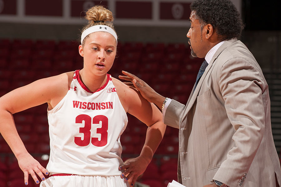 Coach offering advice to a female player during a UW Women's basketball game