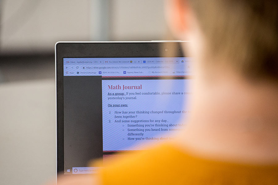 person in front of laptop screen looking at a Math Journal