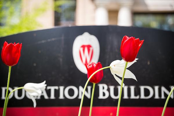 Education building sign with white and red tulips in the foreground.